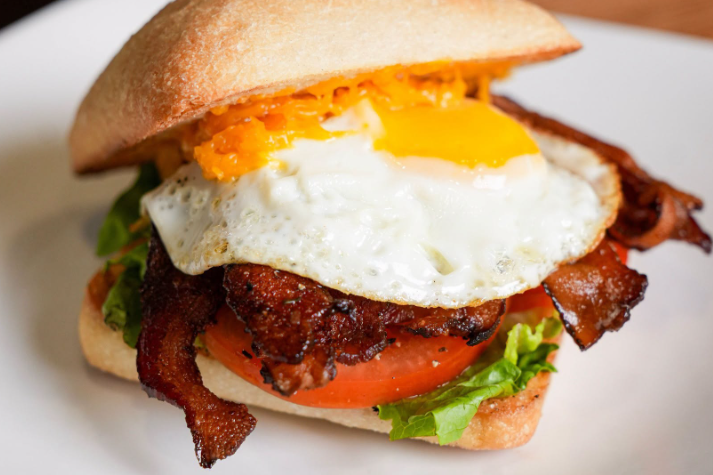 picture of a sandwich with bacon, lettuce, tomato and a fried egg on a plate